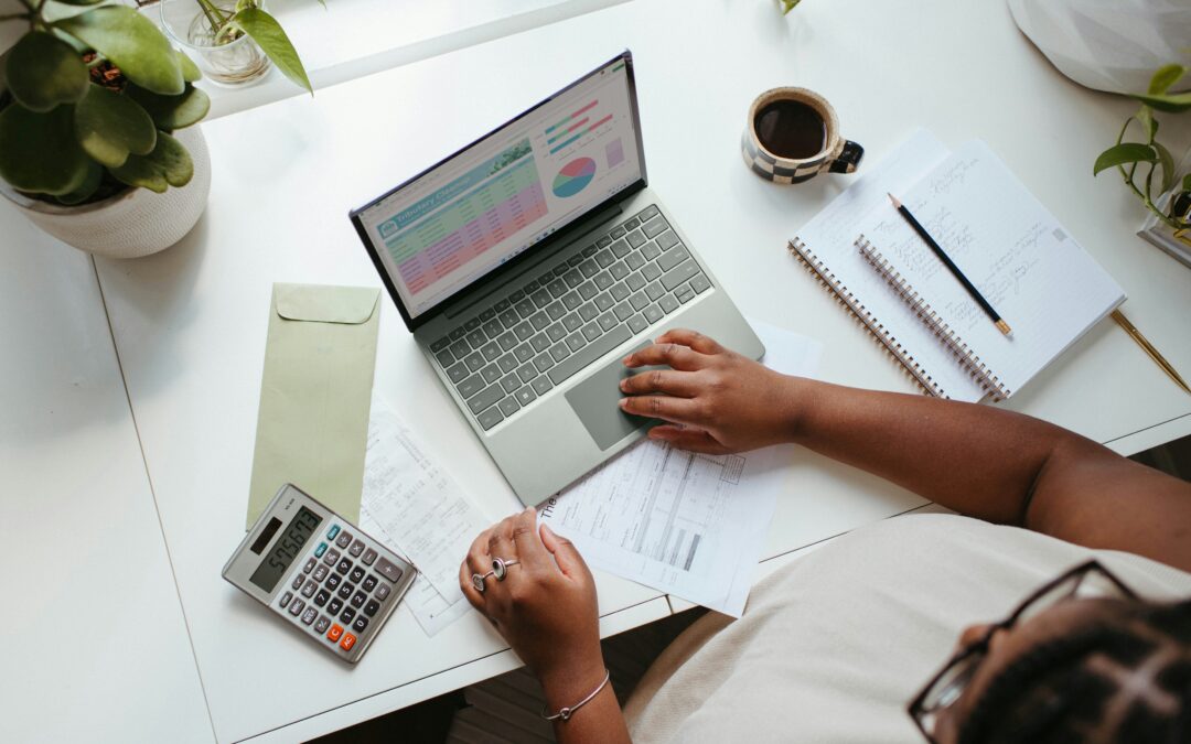 Aerial photo of laptop and other papers, calculator, coffee on desk with person hands controlling laptop_part-time CFO_Summit CFO