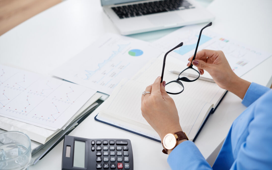 person looking at financial documents and holding glasses